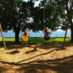 Children swinging in shady park